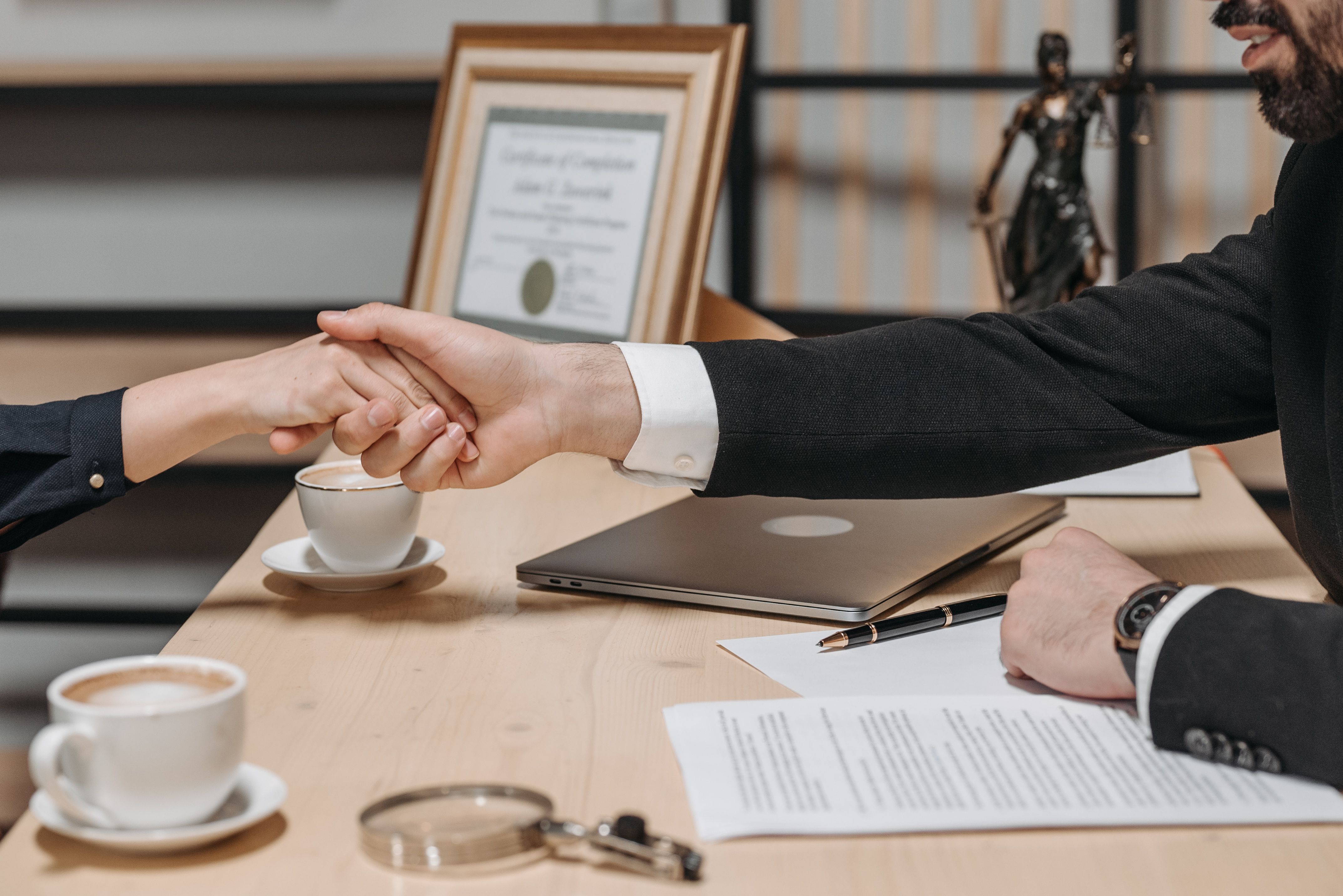 A formal handshake over a business contract in a corporate office setting