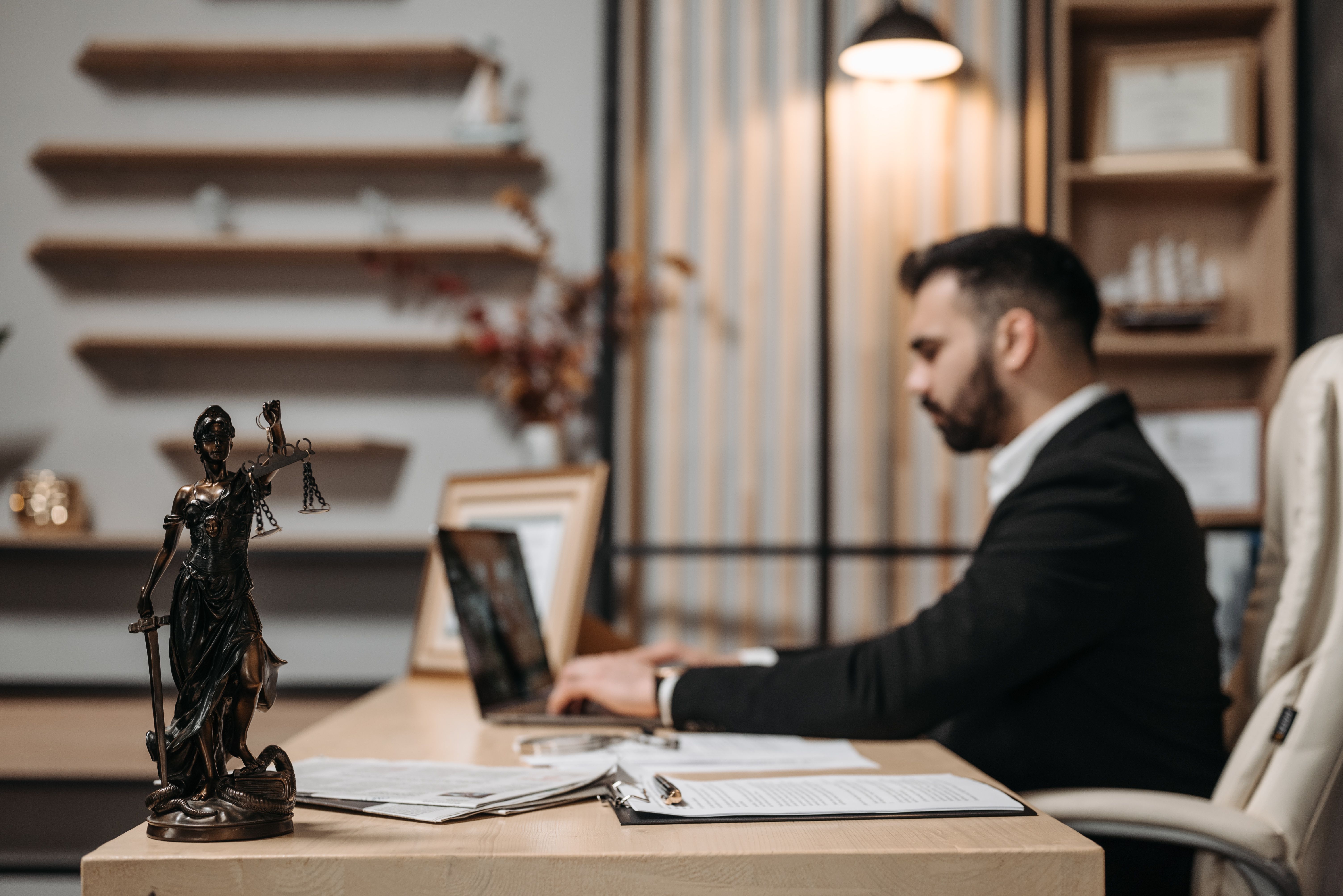 Lawyer working on a laptop in a modern office with a Lady Justice statue, representing billable hours
