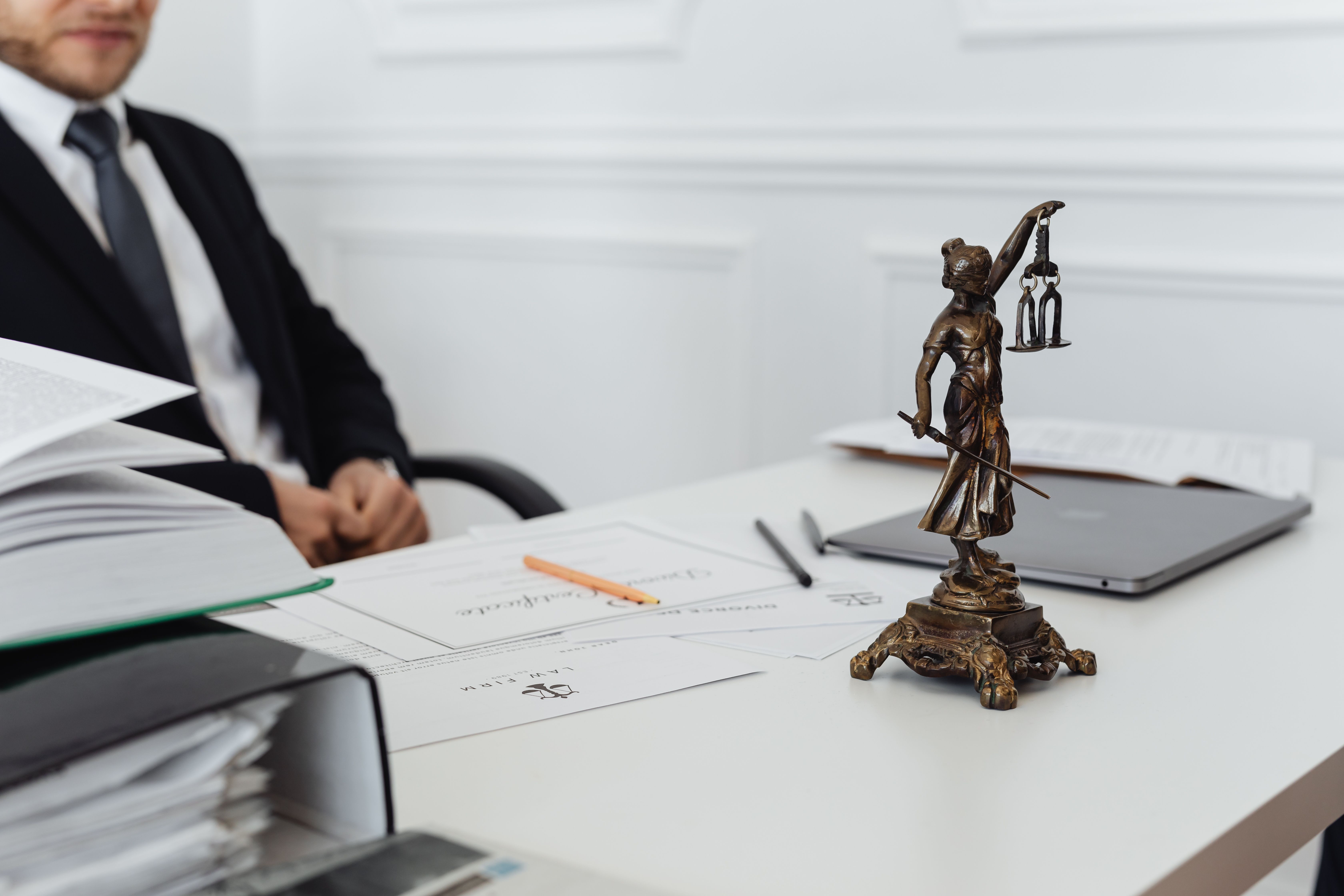 Legal workspace with Lady Justice, documents, and a laptop representing financial pressure from legal case costs.