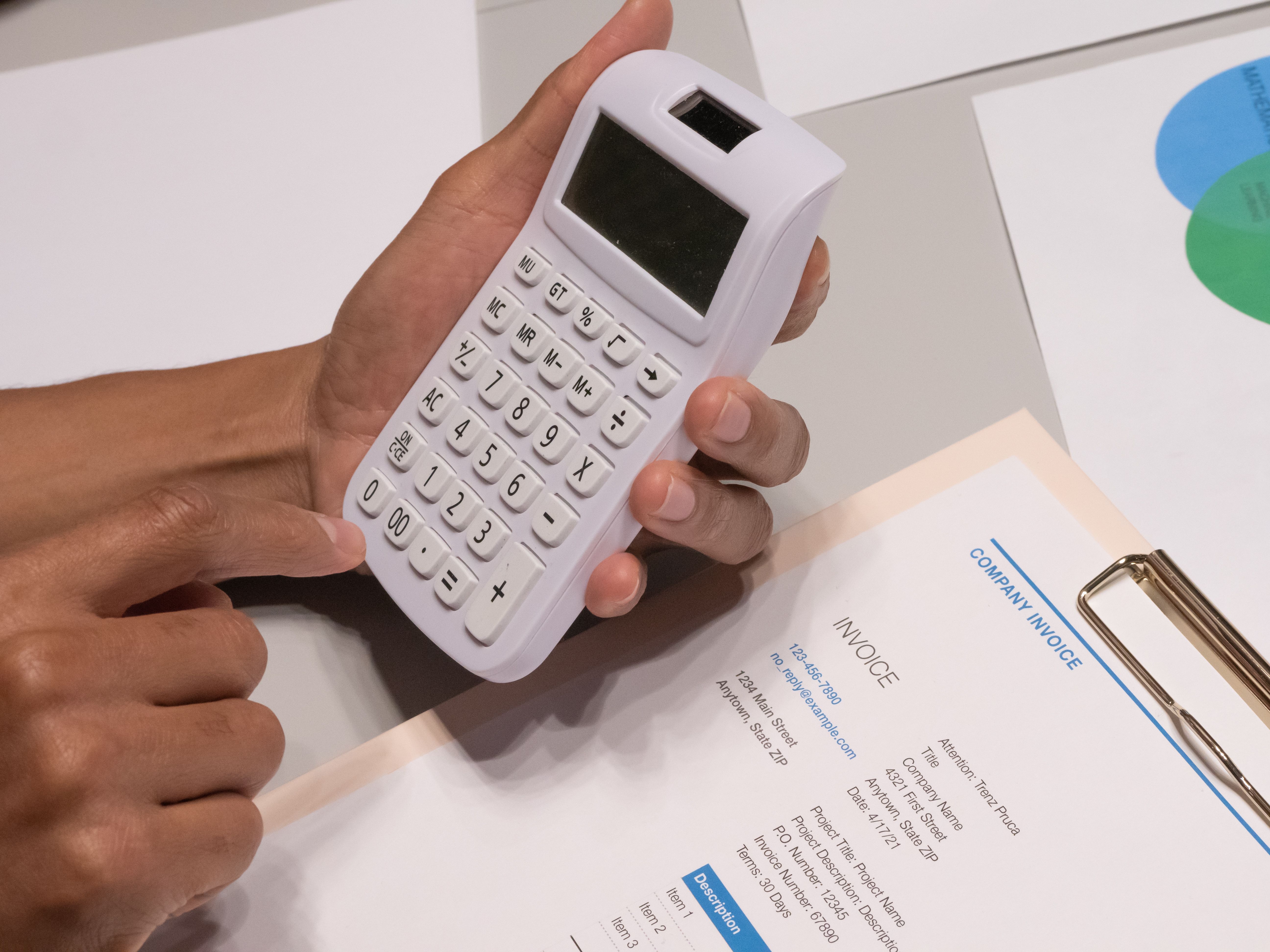 Close-up of hands using a calculator next to an invoice, depicting legal fee calculation and billing