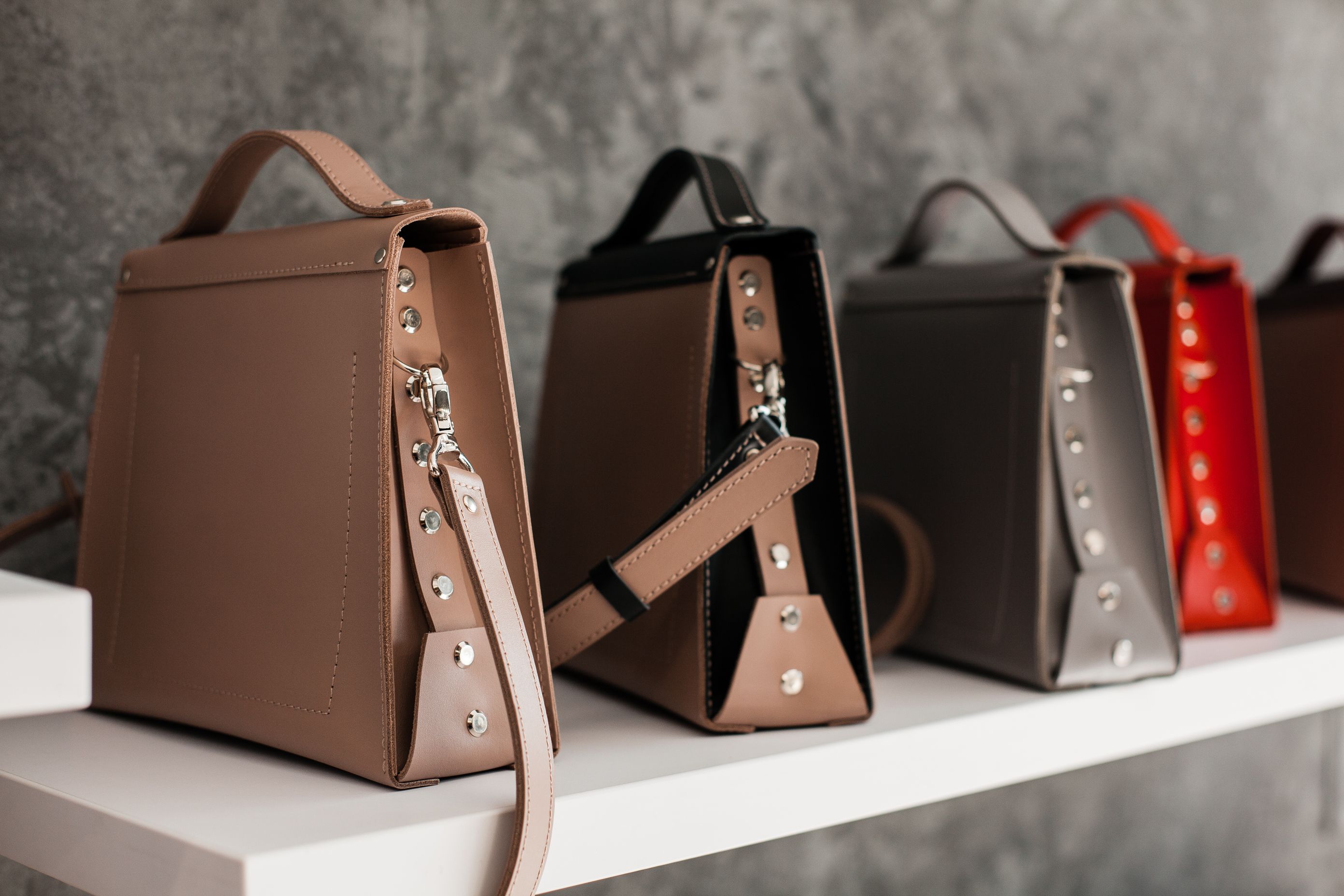 Luxury leather handbags arranged on a minimalist boutique shelf