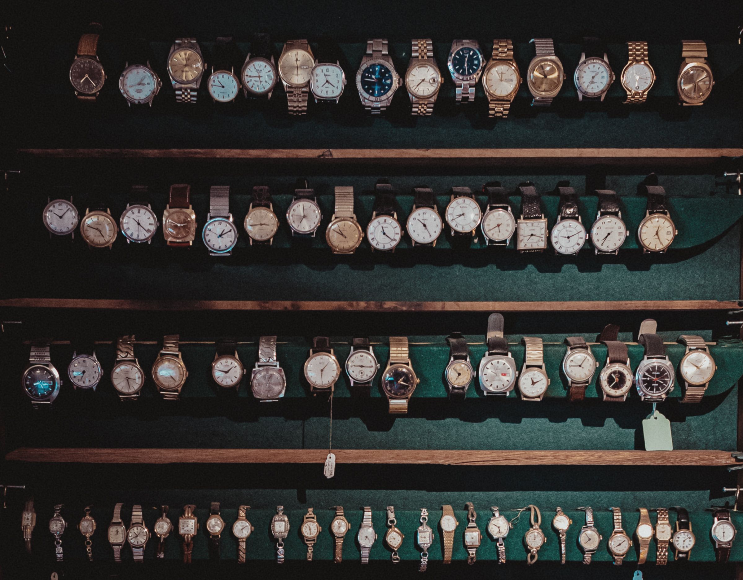 Vintage wristwatches arranged on dark wooden shelves as collectible luxury goods